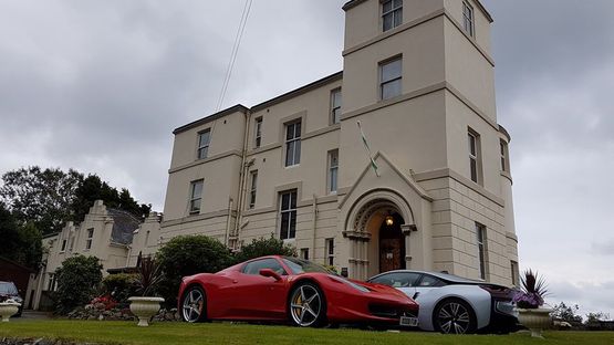 Two sports cars parked outside of Ty’r Graig Castle